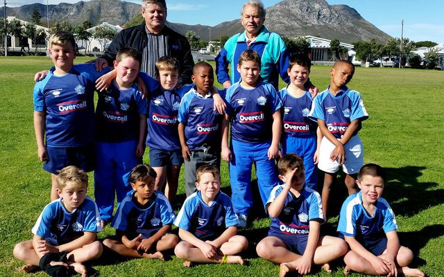 Gansbaai Laerskool se onder 8-rugbyspan speel hierdie kwartaal in netjiese nuwe truie danksy borgskap van die plaaslike Selfoononderneming, Overcell. Agter die spelers staan Francois van der Westhuizen (links), eienaar van Overcell, en Gerrit Cloete, afrigter van die span, nÃ¡ die oorhandiging van die truie.